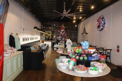 A festive interior of a shop with a Christmas tree, decorated tables, and holiday treats displayed.