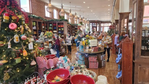 A bustling store decorated for the holidays, filled with shoppers browsing various festive items and gifts.