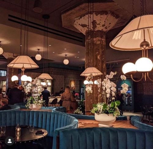 A stylish restaurant interior featuring blue seating, elegant lighting, and decorative plants in a warm ambiance.