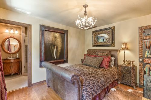 Cozy bedroom featuring a large bed, decorative elephant artwork, and warm lighting.