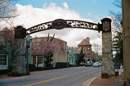Archway sign welcoming visitors to Temecula, established in 1859, with blooming trees and a charming street scene.