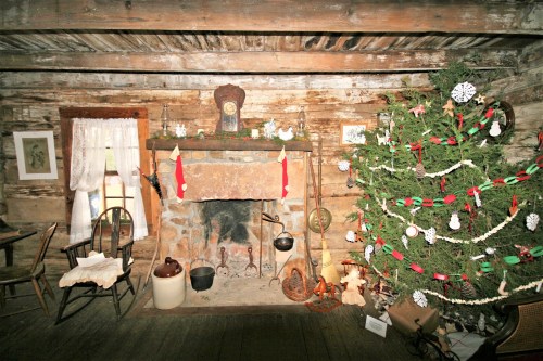Cozy rustic interior with a stone fireplace, decorated Christmas tree, and wooden furniture. Warm holiday atmosphere.