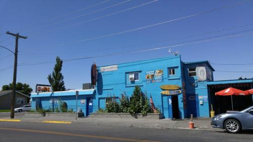 A bright blue building with signage, surfboards, and outdoor seating under a clear blue sky.