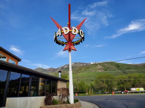 A retro sign for a diner with mountains in the background and a clear blue sky.