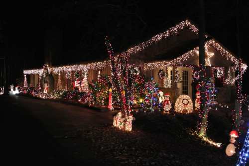 A house decorated with colorful Christmas lights and festive decorations, glowing warmly in the night.