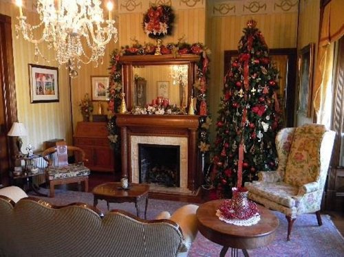 Cozy living room decorated for the holidays, featuring a Christmas tree, fireplace, and festive ornaments.