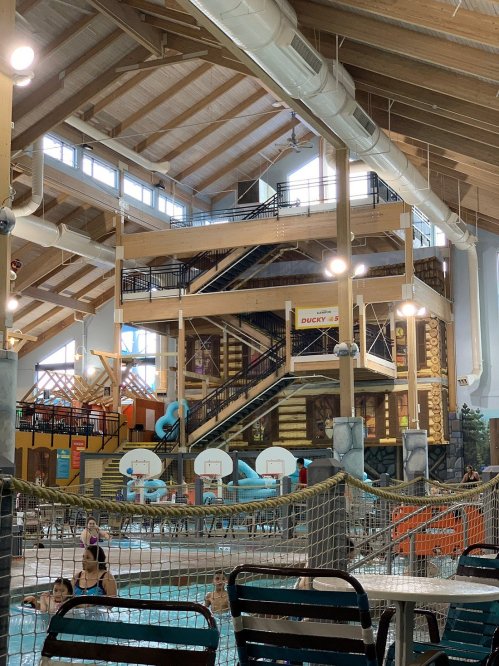 Indoor water park featuring multiple levels, slides, and a pool area with people enjoying the facilities.
