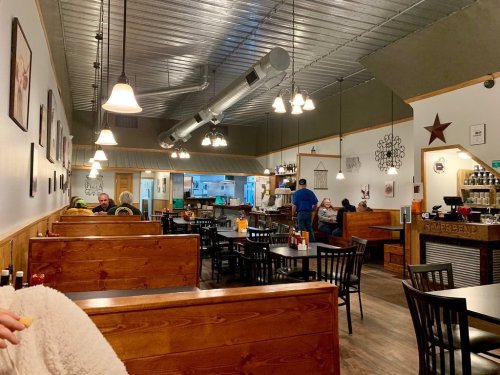 Cozy restaurant interior with wooden tables, chairs, and warm lighting; patrons enjoying their meals in a relaxed atmosphere.