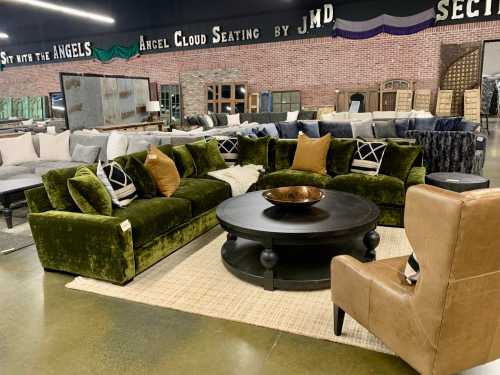 A stylish furniture display featuring a green sectional sofa, a round coffee table, and a tan armchair in a showroom.