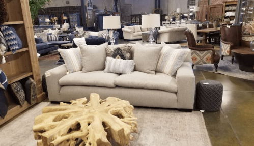 A cozy living room setup featuring a light gray sofa with decorative pillows and a unique wooden coffee table.