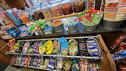 A colorful display of various candies and snacks in bins and containers at a candy shop.