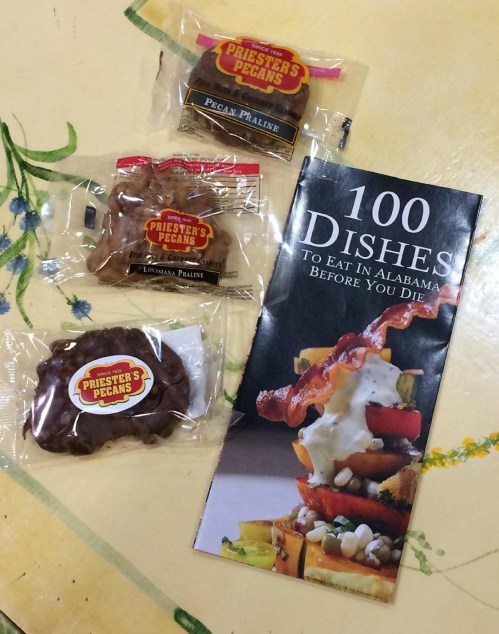 Three packages of praline candies and a brochure titled "100 Dishes to Eat in Alabama Before You Die."