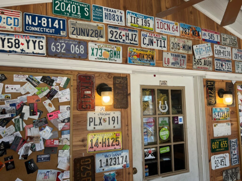 A wall decorated with various U.S. license plates and a bulletin board filled with notes and cards.