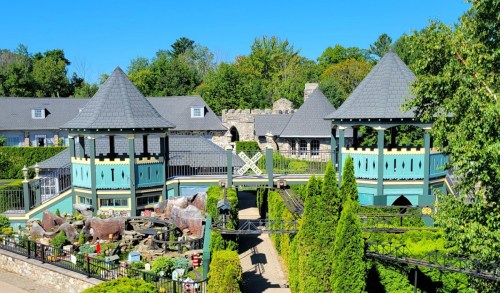 A scenic view of a garden with two towers, surrounded by greenery and a clear blue sky.