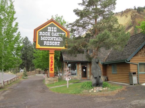 Sign for Big Rock Canyon Mountain Resort with a bear statue in front of a rustic building surrounded by trees.