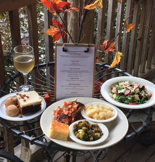 A table with a menu, a glass of beer, and a plate of assorted dishes including salad, cornbread, and dessert.
