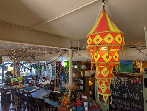 Colorful lantern hanging in a cozy, decorated café with string lights and a welcoming atmosphere.