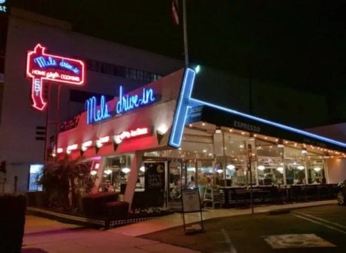 A retro diner at night, featuring neon lights and a welcoming outdoor seating area.