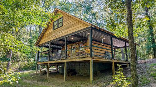 A wooden cabin with a porch, surrounded by trees in a lush green forest.