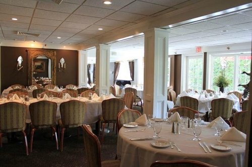 Elegant restaurant interior with round tables set for dining, featuring white tablecloths and tasteful decor.