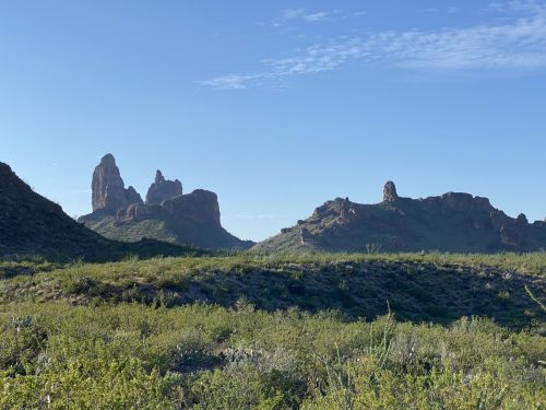 A scenic view of rugged mountains and green vegetation under a clear blue sky.