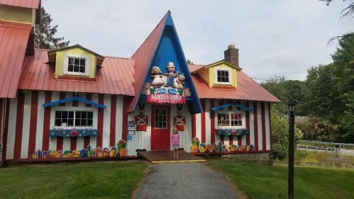 A colorful, whimsical building with red and white stripes, featuring a blue triangular roof and cartoon characters on the facade.