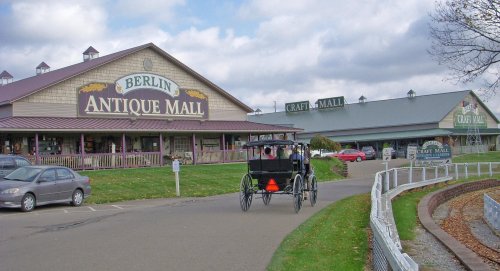 A view of Berlin Antique Mall with a horse-drawn carriage in the foreground and craft mall buildings in the background.