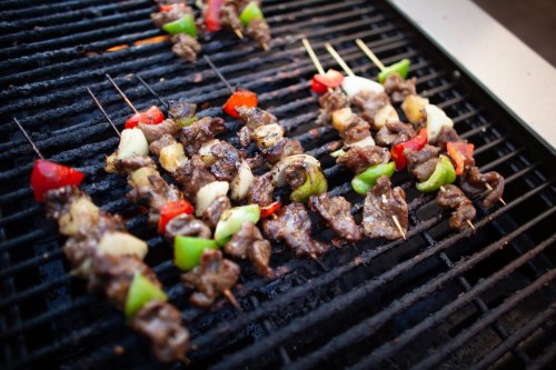 Grilled skewers of meat and colorful vegetables cooking on a barbecue grill.