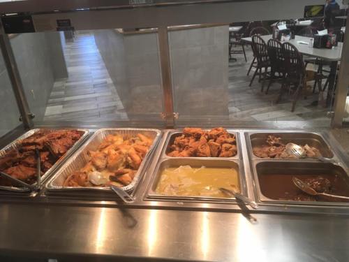 A buffet display with various dishes, including fried chicken, pastries, and sauces, in a restaurant setting.