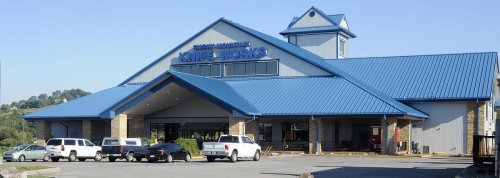 A large building with a blue roof and sign reading "Marine & Outdoor," surrounded by parked cars and greenery.