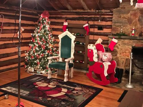 Cozy holiday scene with a decorated Christmas tree, Santa-themed rug, rocking horse, and festive stockings.