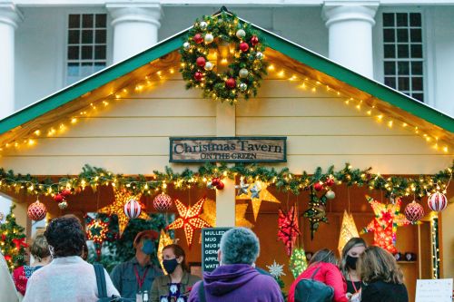 A festive Christmas tavern decorated with lights and ornaments, bustling with visitors during the holiday season.