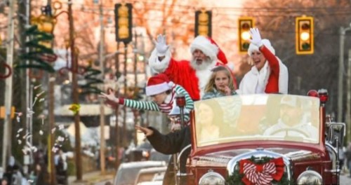 A festive parade scene with Santa, children, and adults waving from a vintage car, surrounded by holiday decorations.