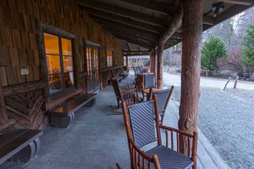 A rustic porch with wooden rocking chairs and a cozy atmosphere, surrounded by nature.