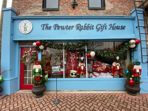 A festive storefront decorated for the holidays, featuring nutcrackers, garlands, and a sign reading "The Pewter Rabbit Gift House."