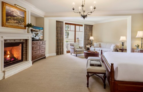 Cozy hotel room featuring a fireplace, seating area, large windows, and elegant decor.