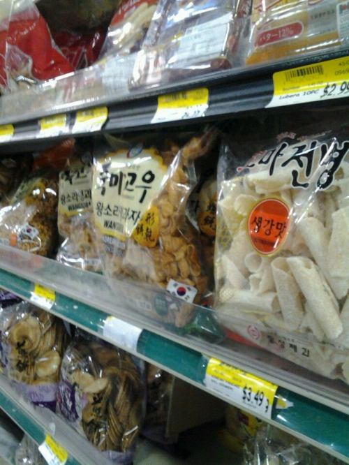 A grocery store shelf displaying various bags of snacks, including dried fish and other packaged foods.