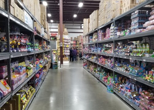 A wide aisle in a store filled with colorful toys and products on both sides, with people in the background.