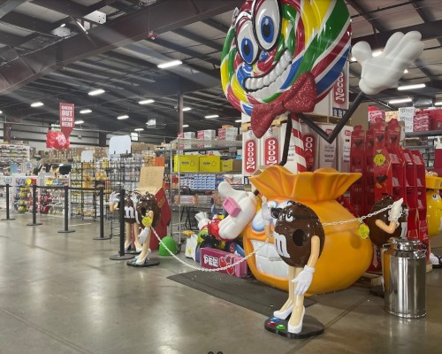 A colorful candy store interior featuring large candy-themed decorations and displays of various sweets.