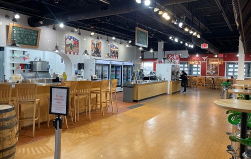 A spacious, modern restaurant interior with seating, a service counter, and a menu display. Brightly lit and inviting.