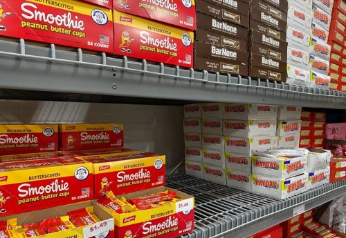 Shelves stocked with various brands of peanut butter cups and candy boxes, including Smoothie and BarNone.