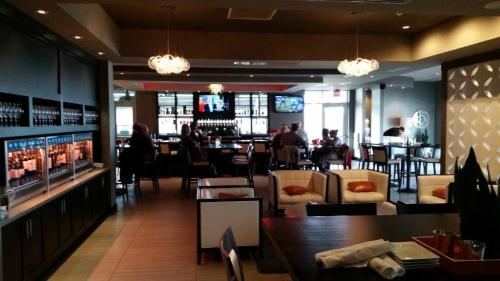 A modern restaurant interior with a bar, seating areas, and patrons enjoying their meals in a stylish atmosphere.