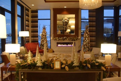 Cozy lobby decorated for the holidays, featuring Christmas trees, elegant lighting, and a fireplace.