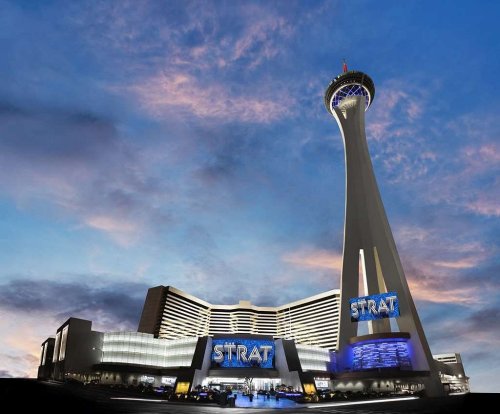 The Strat hotel and casino in Las Vegas, featuring a tall observation tower against a colorful sunset sky.