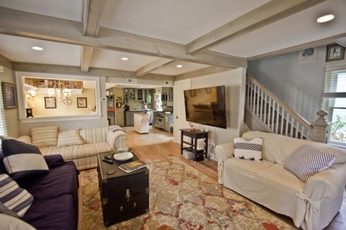 Cozy living room with a purple sofa, white couch, wooden coffee table, and a large TV, featuring a warm, inviting atmosphere.