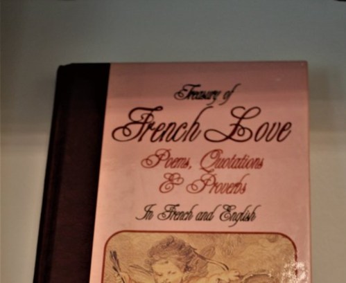 A book titled "Treasure of French Love" featuring poems, quotations, and proverbs in French and English.