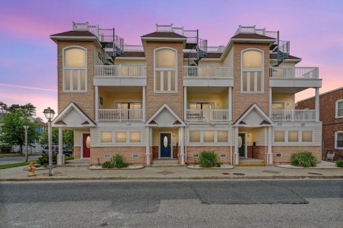 A multi-story residential building with balconies, set against a colorful sunset sky.