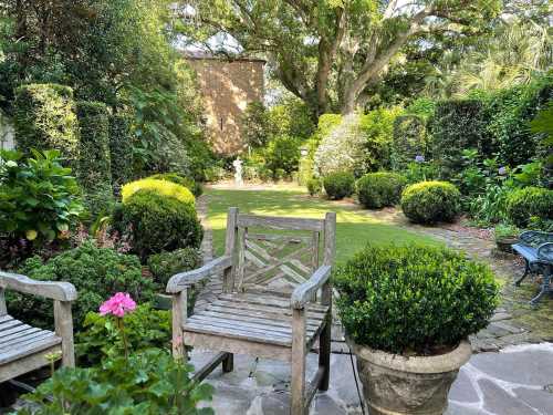 A serene garden scene featuring lush greenery, a stone path, and wooden chairs surrounded by vibrant plants.