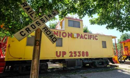 A yellow Union Pacific caboose next to a wooden railroad crossing sign.