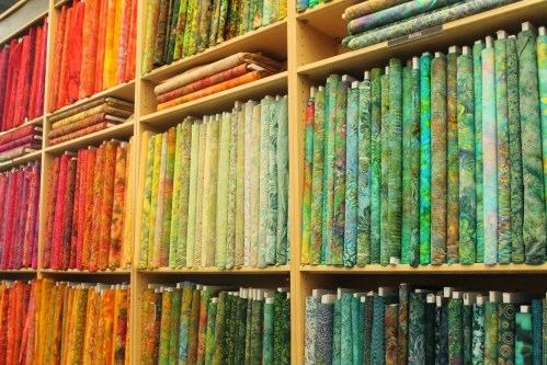 A vibrant display of rolled fabric in various colors, arranged neatly on shelves.